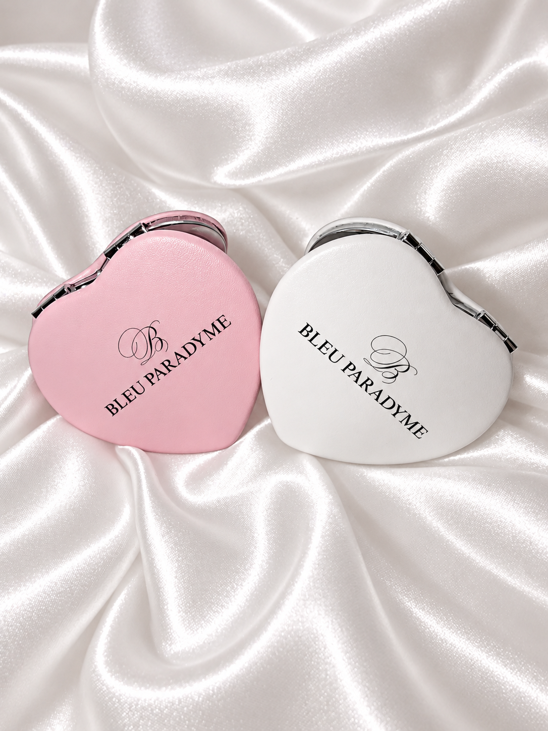 Pink and white Bleu Paradyme compact mirrors on pearl satin
