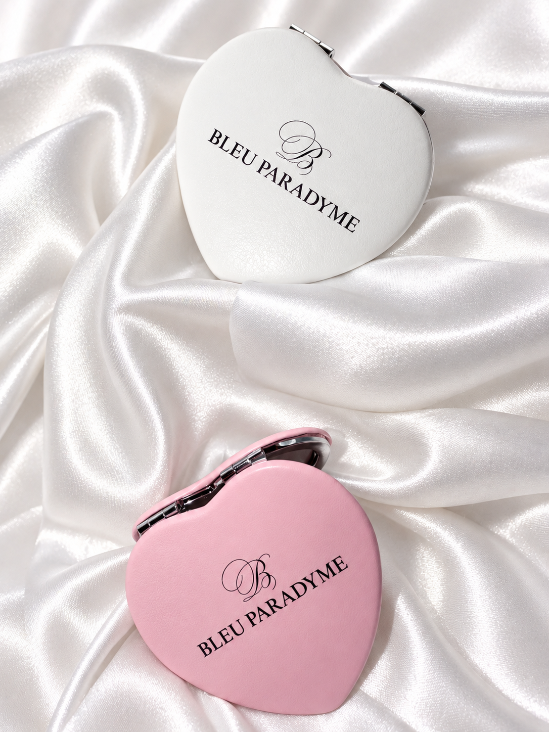 Two Bleu Paradyme heart mirrors arranged vertically on pearl satin