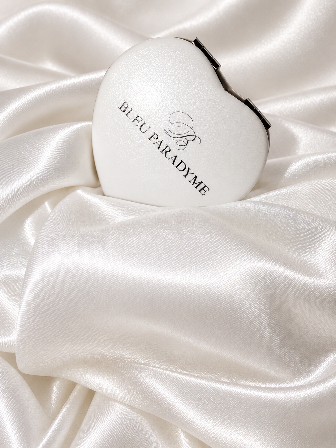 White Bleu Paradyme heart compact on white satin